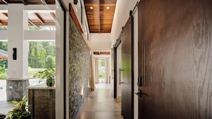 A hallway with a stone wall, wooden ceiling, and a large wooden door.