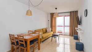 A living room with a sofa, a dining table with chairs, and two pendant lights. - 2BR BuenaVida Residential - Mountain Views 2ºD (Breña baja)