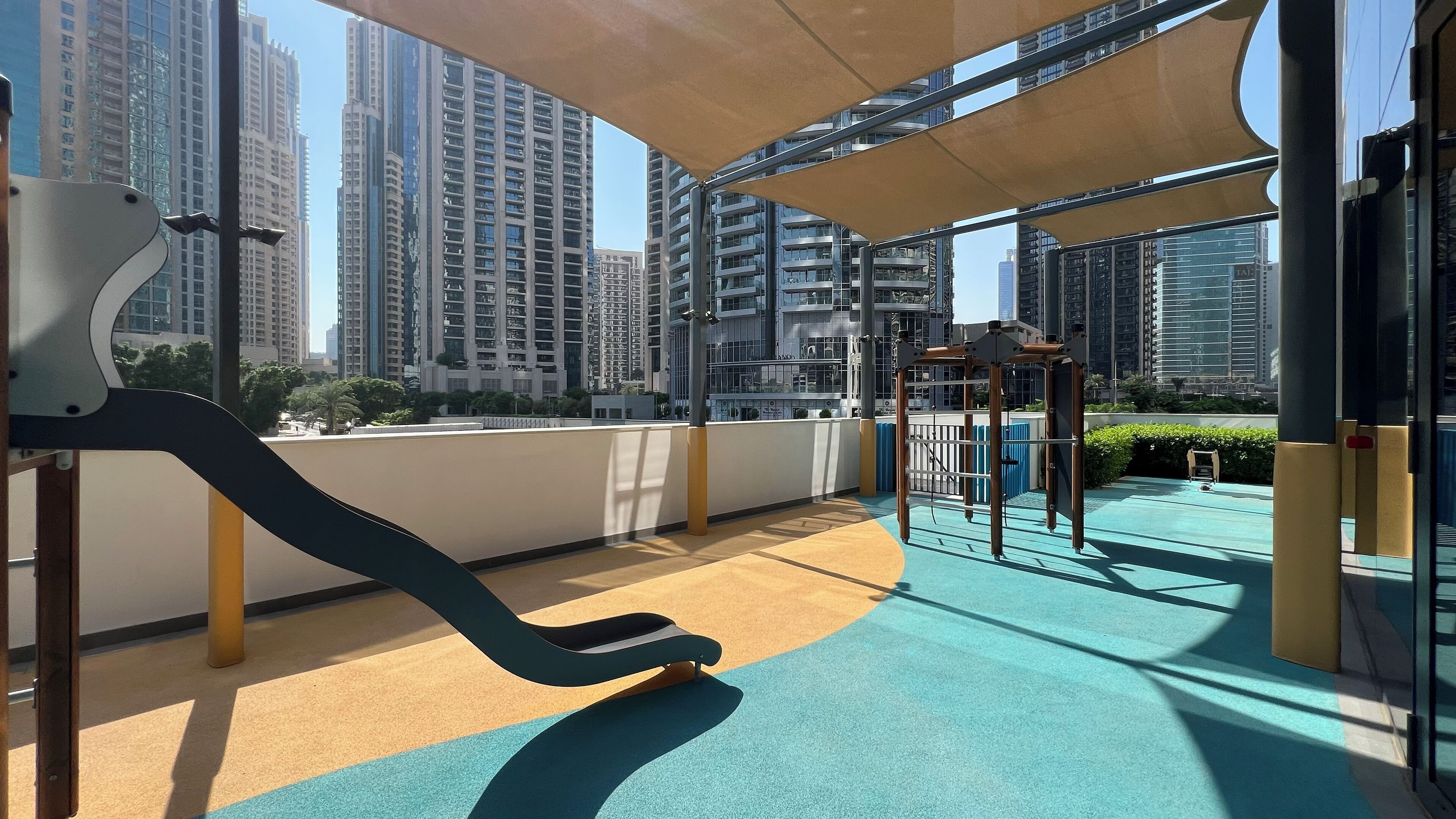 A rooftop playground with exercise equipment and a view of high-rise buildings.