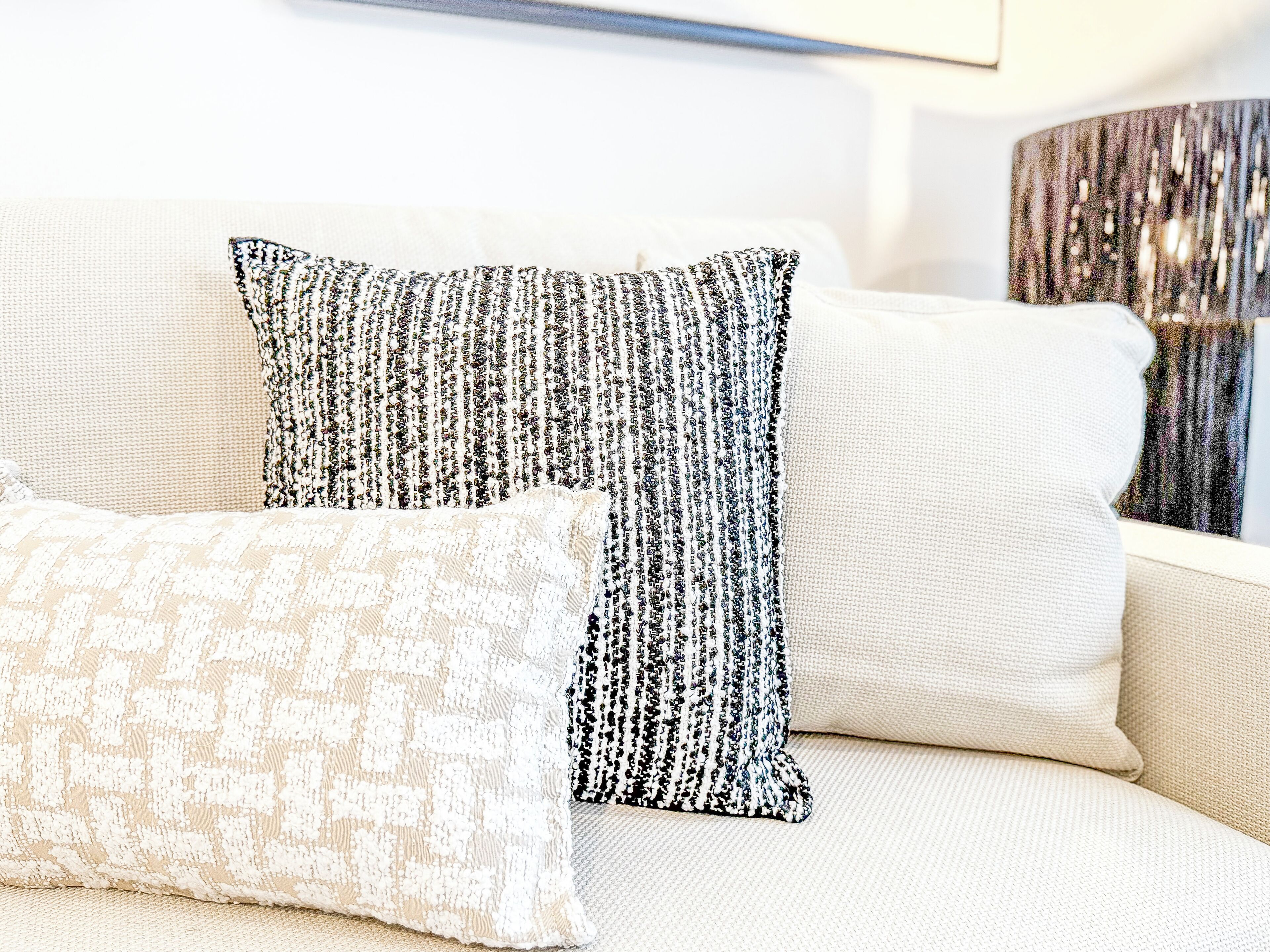 A sofa with two pillows, one with a black and white pattern and the other with a beige and white pattern.