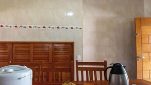 Una habitación con cabecera de madera, dispensador de agua blanco, hervidor eléctrico negro y puerta de madera.