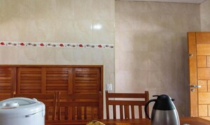 A kitchen with a wooden cabinet, a white appliance, a coffee maker, and a plate of bananas.