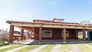 Un espacio al aire libre cubierto con un edificio de ladrillo, una pérgola y cielo despejado.