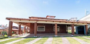 A two-story house with a covered patio, brick exterior, and a clear sky.
