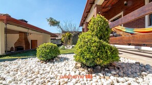 A courtyard with a brick fireplace, a hammock, and well-maintained bushes. - Casa de campo em Cotia com piscina e lazer (Cotia)