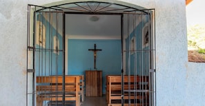 Ein Kircheninneres mit hölzernen Kirchenbänken, einem hölzernen Altar und einem Kreuz an der Wand.