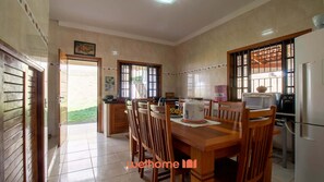 A dining area with a wooden table and chairs, a refrigerator, and a microwave.