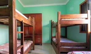 Ein Schlafraum mit Etagenbett, Holzschrank und Fenster.