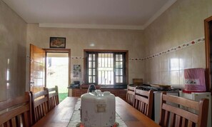 A spacious kitchen with a long wooden table, a gas stove, and a refrigerator. - Casa de campo em Cotia com piscina e lazer (Cotia)