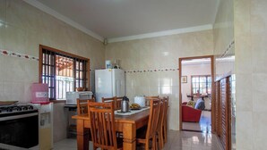 Una cocina con una mesa de comedor, sillas, estufa y refrigerador.