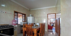 A kitchen with a dining table, chairs, a stove, and a refrigerator.