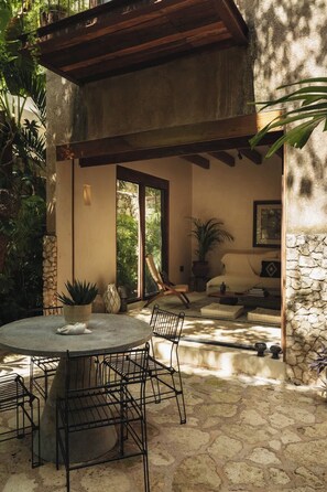 Een buitenterras met een ronde tafel en stoelen, een stenen muur en een houten pergola.