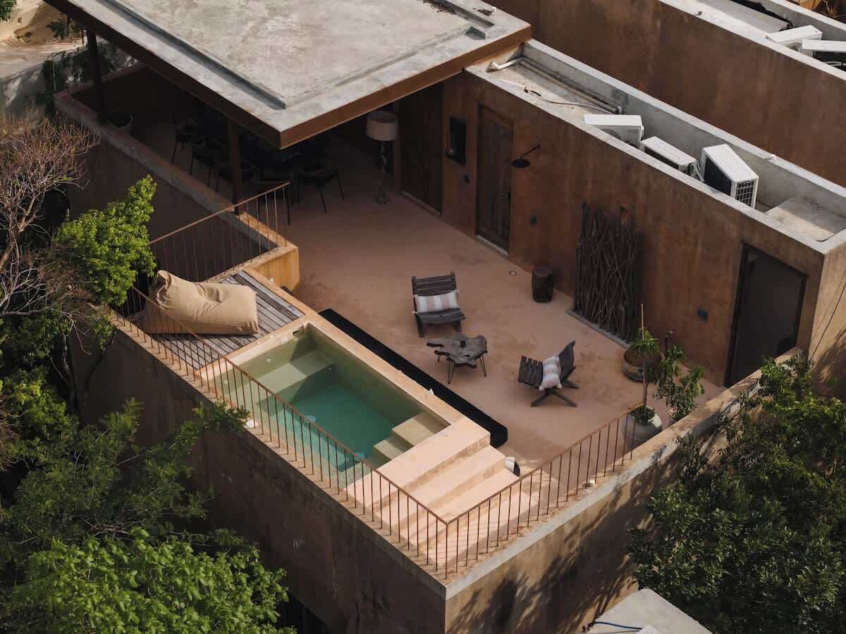 A rooftop pool area with a hot tub, lounge chairs, and a small table.