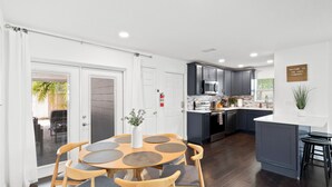 Une cuisine moderne avec des meubles de couleur sombre, un plan de travail blanc et un îlot central.