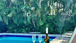 Une table, deux verres et une bouteille de champagne, le tout installé au bord d’une piscine.