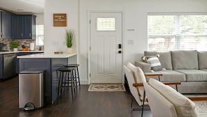 A modern kitchen with dark wood flooring, a white door, and a bar area with stools. - Private Resort Villa | Heated Pool + Game Room + Near Gulf Beaches (Largo)