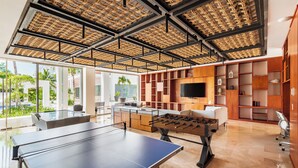 A spacious room with a ping pong table, a foosball table, and a large TV. - La Amada Private Terrace (Cancún)