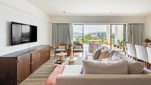 A modern living room with a sofa, chairs, a TV, and a balcony with a view of buildings. - La Amada Private Terrace (Cancún)