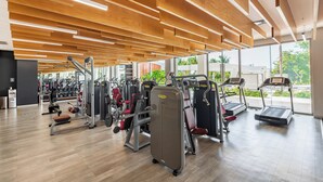 A gym with various exercise equipment, wooden ceiling design, and large windows. - La Amada Private Terrace (Cancún)