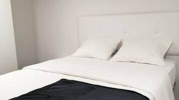 A bed with white bedding and a black throw blanket.