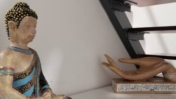 A statue of a seated figure with a decorative headpiece, a wooden hand sculpture, and a patterned box on a white surface.