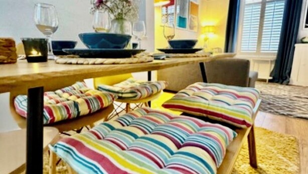 A dining area with a wooden table, striped cushions, and a vase with flowers. - Traditional Belfast House 10 Mins From City Centre (Belfast)