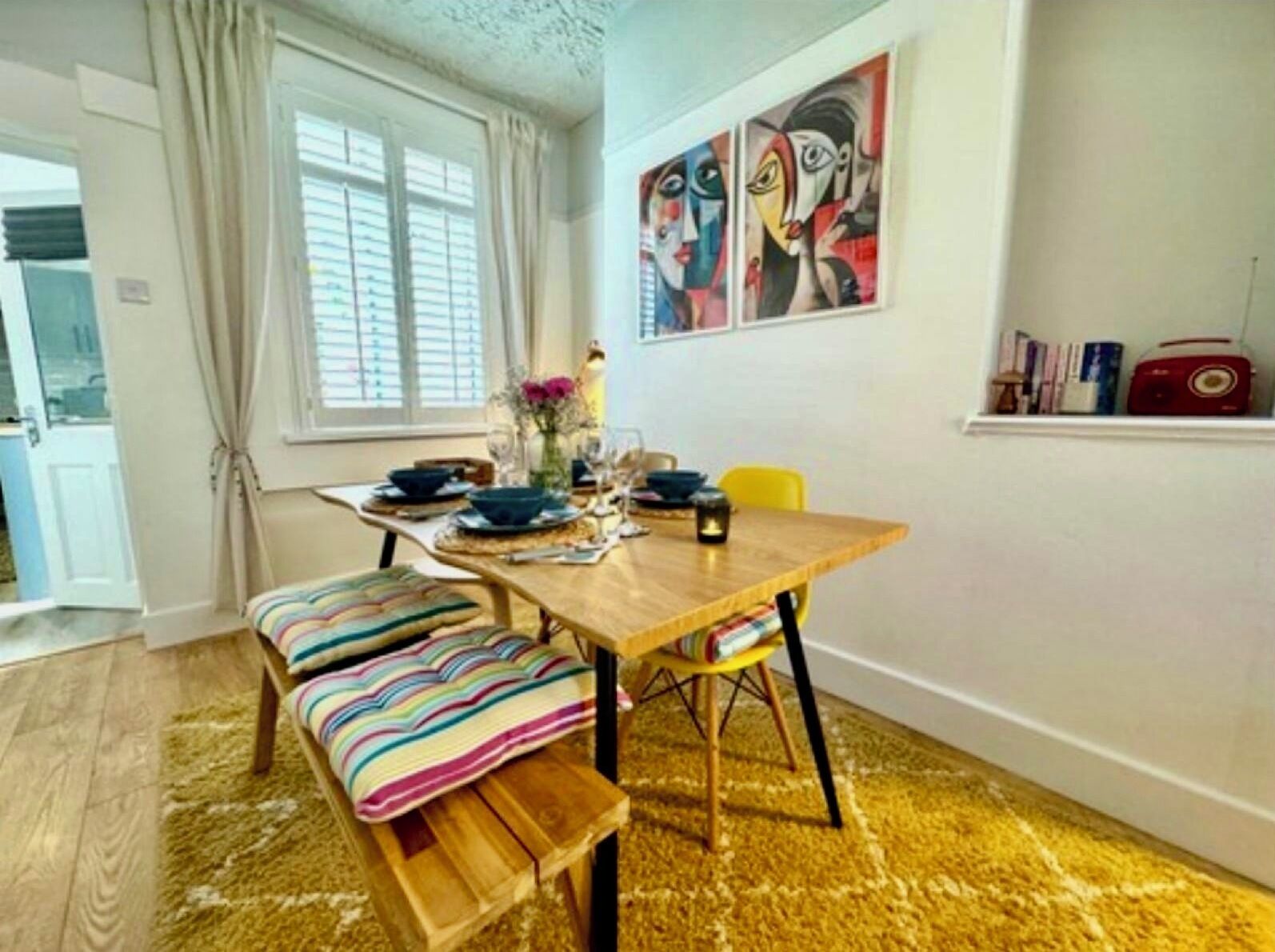 En matplats med ett träbord, bänkar och ett fönster med gardiner.