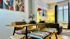 A dining area with a wooden table, benches, and a vase with flowers. There are paintings on the wall and a window with curtains. - Traditional Belfast House 10 Mins From City Centre (Belfast)