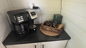 Ett litet kök med en kaffebryggare, ett litet kylskåp och en korg för kaffetilbehör.