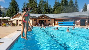 Ein Poolbereich mit einem Gebäude im Hintergrund, umgeben von Bäumen.