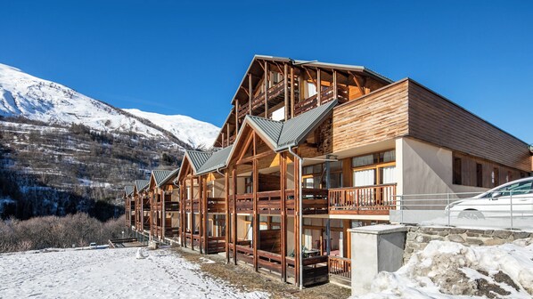 A wooden lodge with multiple balconies and a view of snow-covered mountains. - Le Hameau de Valloire S4p Coin Nuit (Valloire)