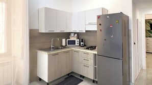A modern kitchen with white cabinets, a stainless steel refrigerator, a microwave, and a gas stove. - Anema& Core house entire accommodation a stone's throw from Via Toledo - Naples (Napoli)