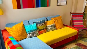 Um quarto com um sofá colorido, um tapete estampado e uma obra de arte vibrante na parede.