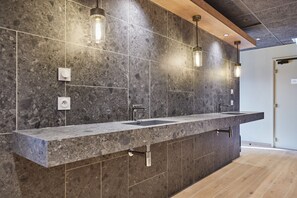 Une salle de bain moderne avec un comptoir en granit, deux vasques et des luminaires suspendus.