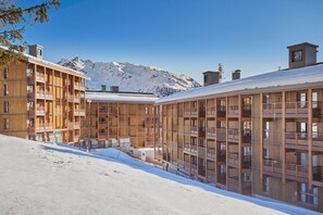 En modern byggnad med flera balkonger och ett snöklätt berg i bakgrunden.