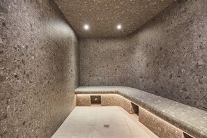 Une salle de spa avec un mur en pierre, un banc et un sol carrelé.