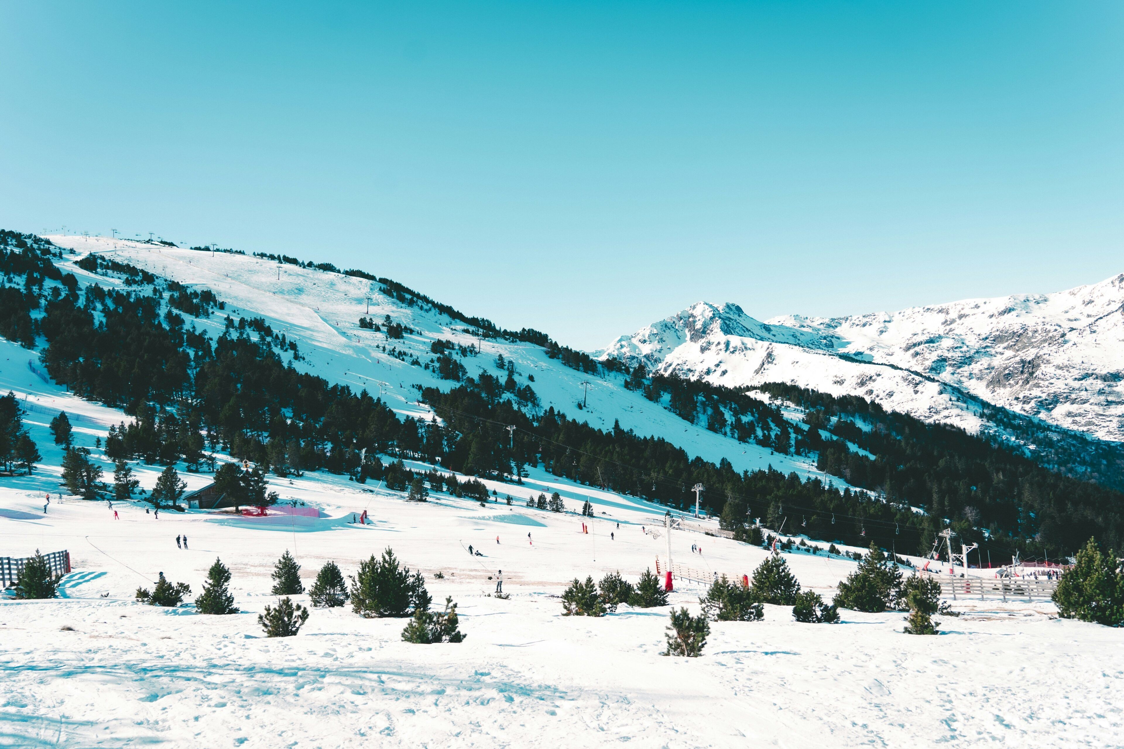 A snowy mountain landscape with ski slopes, trees, and a clear sky.