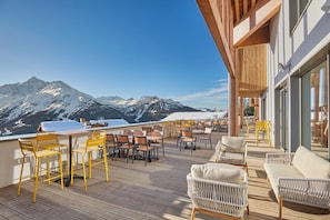 A deck with outdoor seating, a table, and a mountain view.