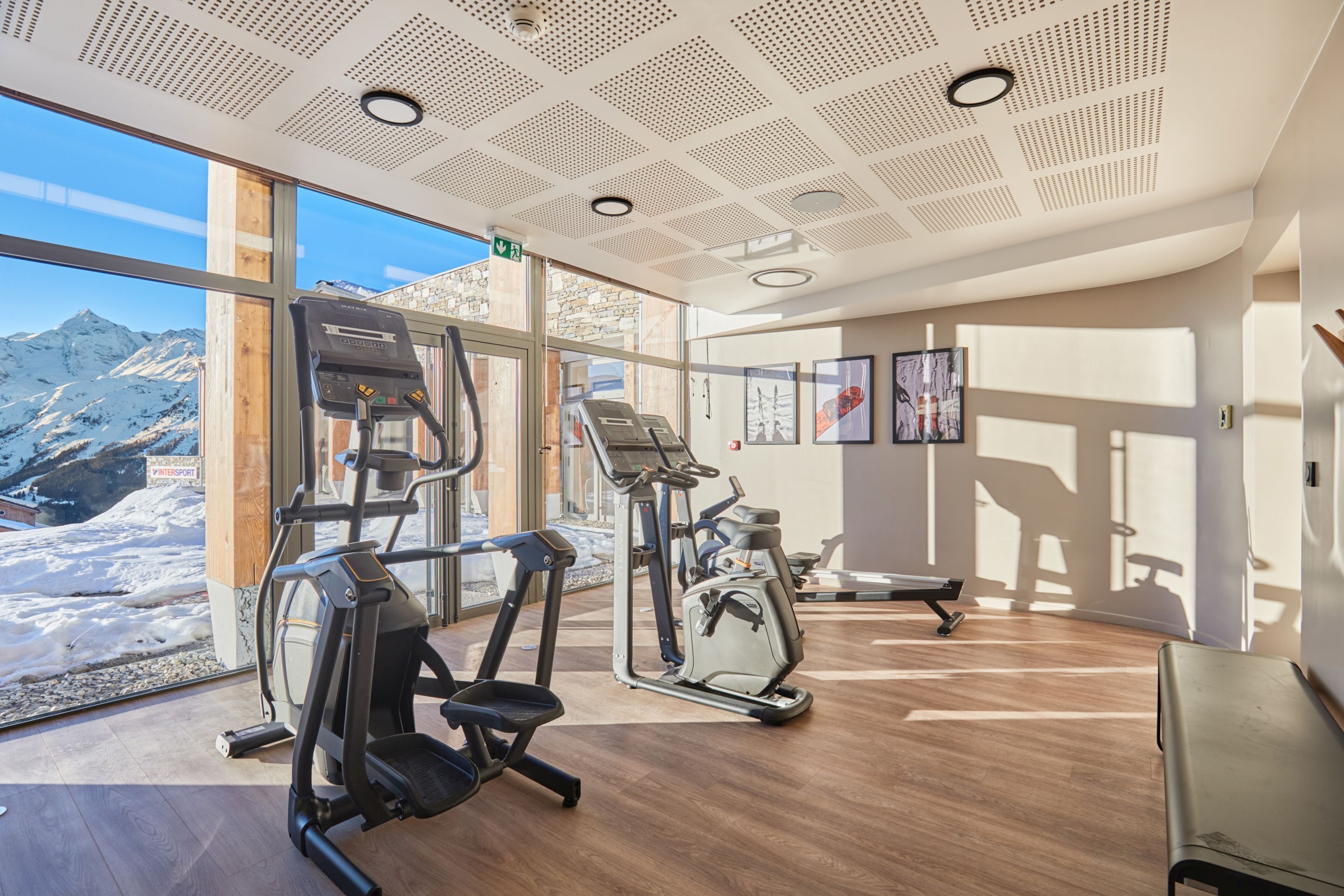 A gym with exercise equipment, large windows, and a view of snow-capped mountains.