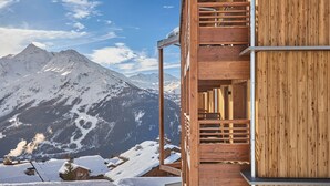 Une cabane en bois dotée d’un balcon donnant sur un paysage montagneux enneigé.