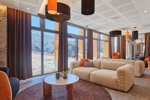 A modern interior with large windows, a sofa, a table, and pendant lights.