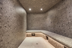 A spa room with a stone wall, a bench, and a tiled floor.
