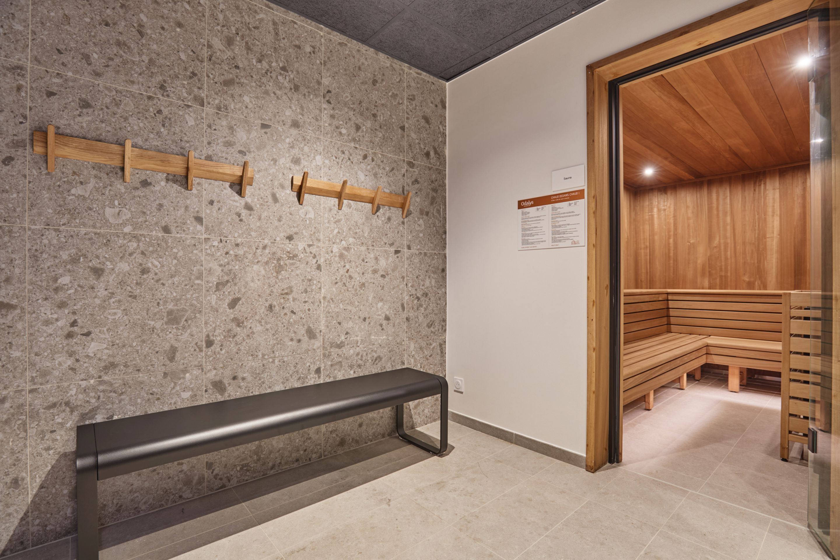 A sauna area with benches, a wooden bench, and a wall-mounted towel rack.