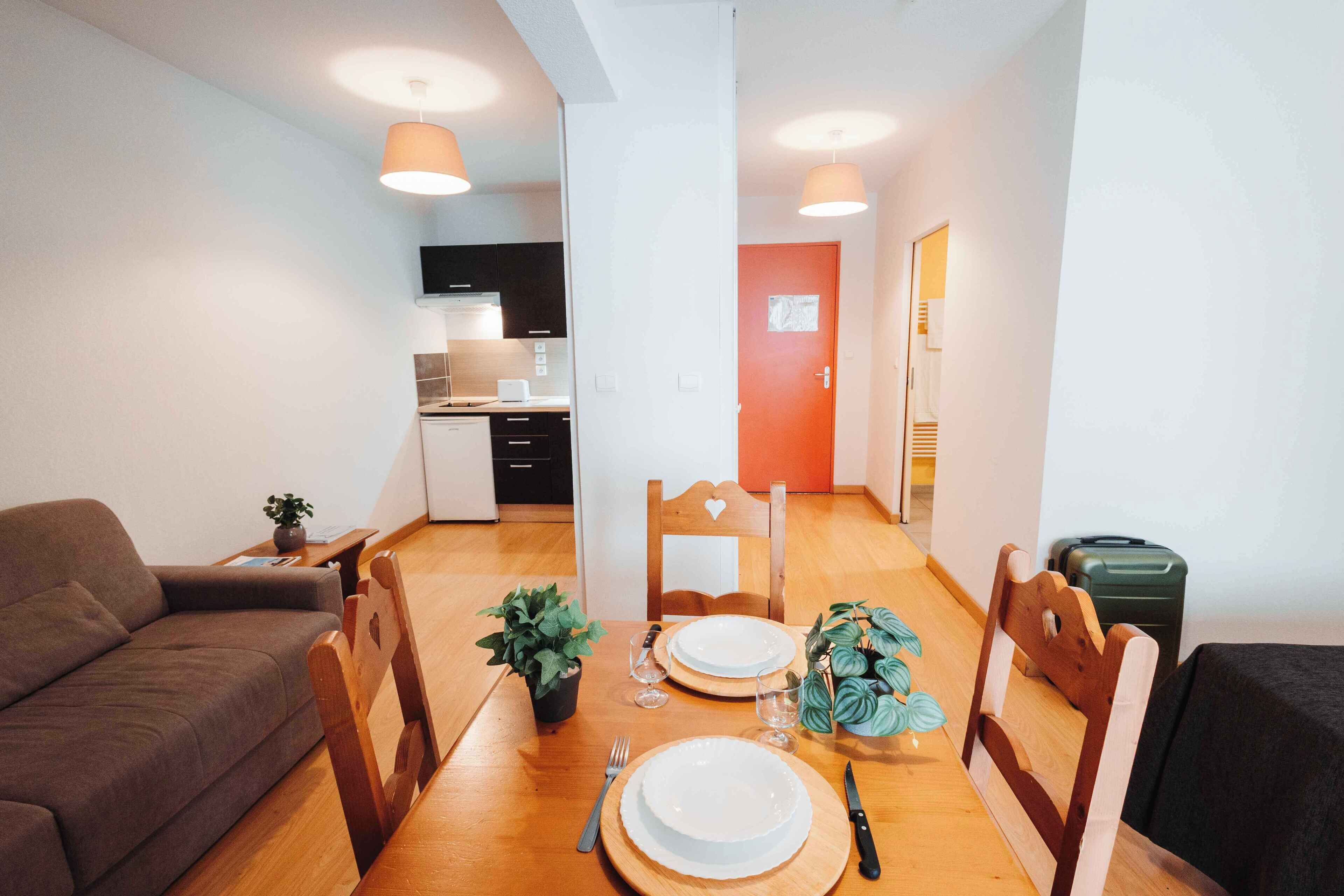 A compact living space with a dining area, kitchenette, and a sofa.