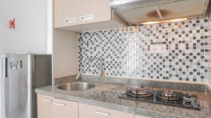 Une cuisine moderne équipée d’un réfrigérateur en acier inoxydable, d’un évier à deux bacs et d’une cuisinière à gaz.