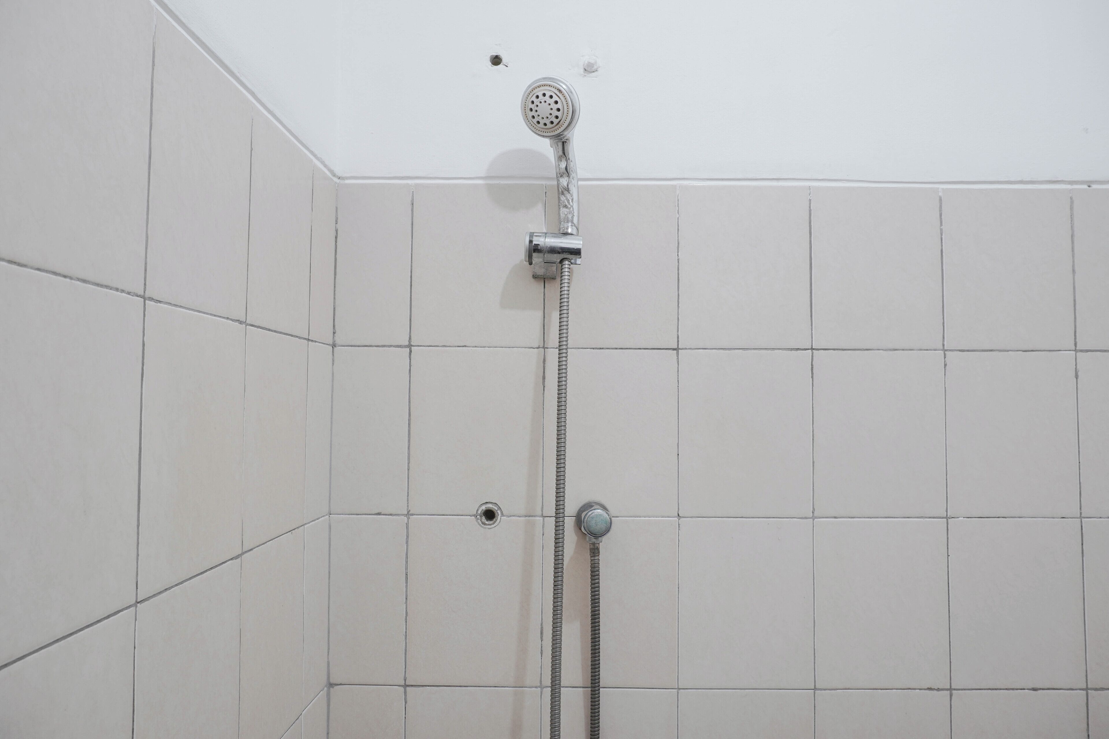 Ein Duschbereich mit Handbrause und am Wand montierter Armatur.
