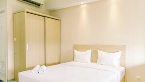 A hotel room with a large bed, two white pillows, and a wooden wardrobe. - Elegant Studio Apartment Silkwood Residences Near Alam Sutera (Tangerang)