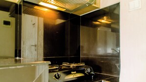 A kitchen with a black stove, white cabinets, and a stainless steel backsplash. - Elegant Studio Apartment Silkwood Residences Near Alam Sutera (Tangerang)