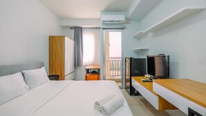 A hotel room with a bed, a desk, a TV, and an air conditioning unit. - Elegant Studio Near Senayan And Pondok Indah At Pakubuwono Terrace Apartment (Jakarta)