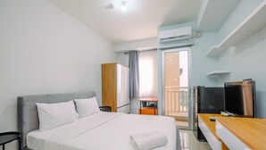 A hotel room with a large bed, a desk with a computer, a TV, and an air conditioning unit. - Elegant Studio Near Senayan And Pondok Indah At Pakubuwono Terrace Apartment (Jakarta)
